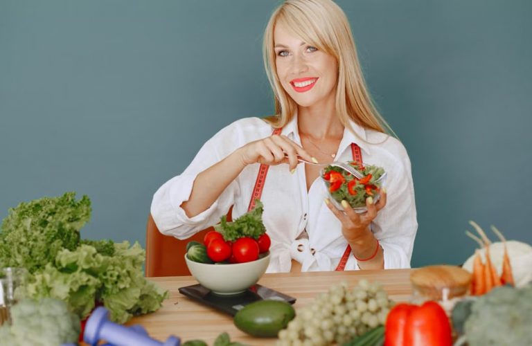 Blonde woman enjoying a fresh salad surrounded by vegetables, promoting healthy eating.